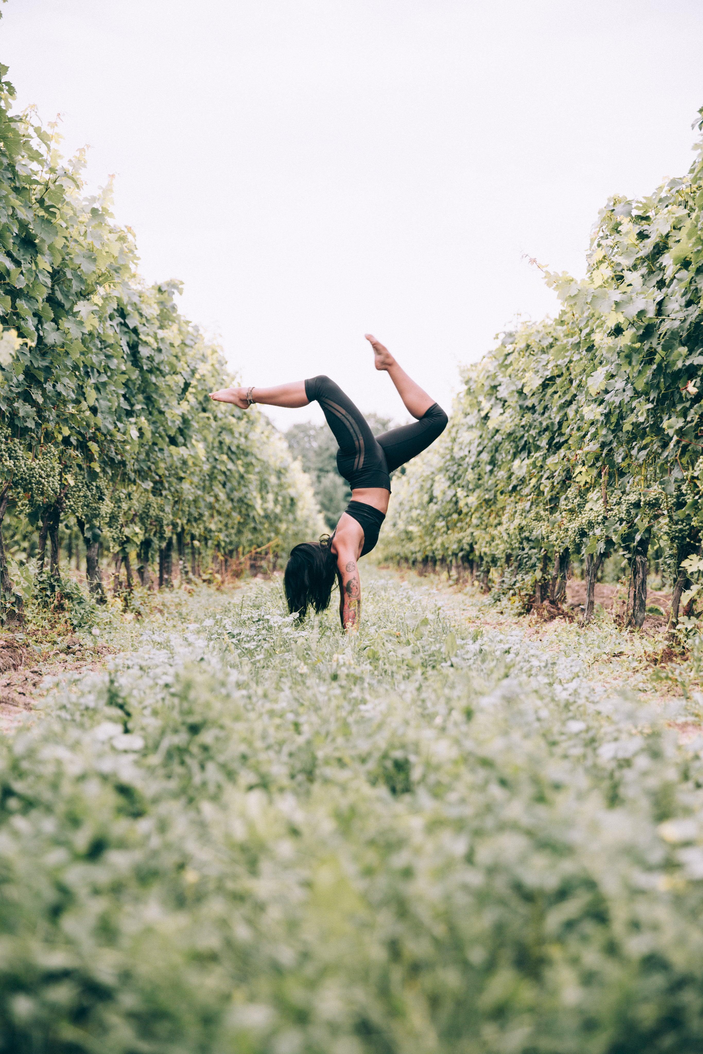 Person performing a handstand and balancing among trees outdoors, showcasing strength, flexibility, and connection with nature