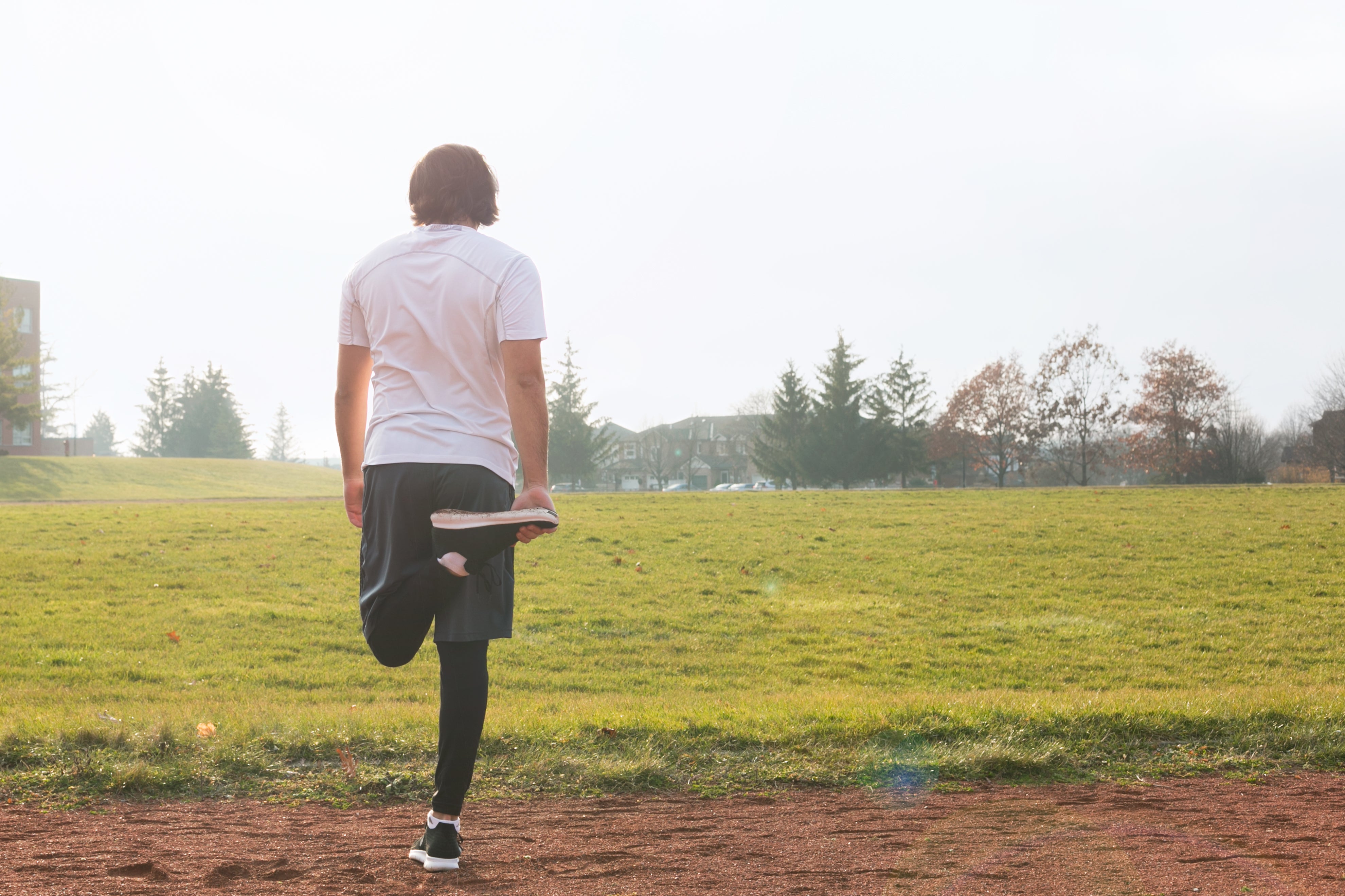 Person stretching their legs before a run, warming up muscles outdoors in preparation for exercise