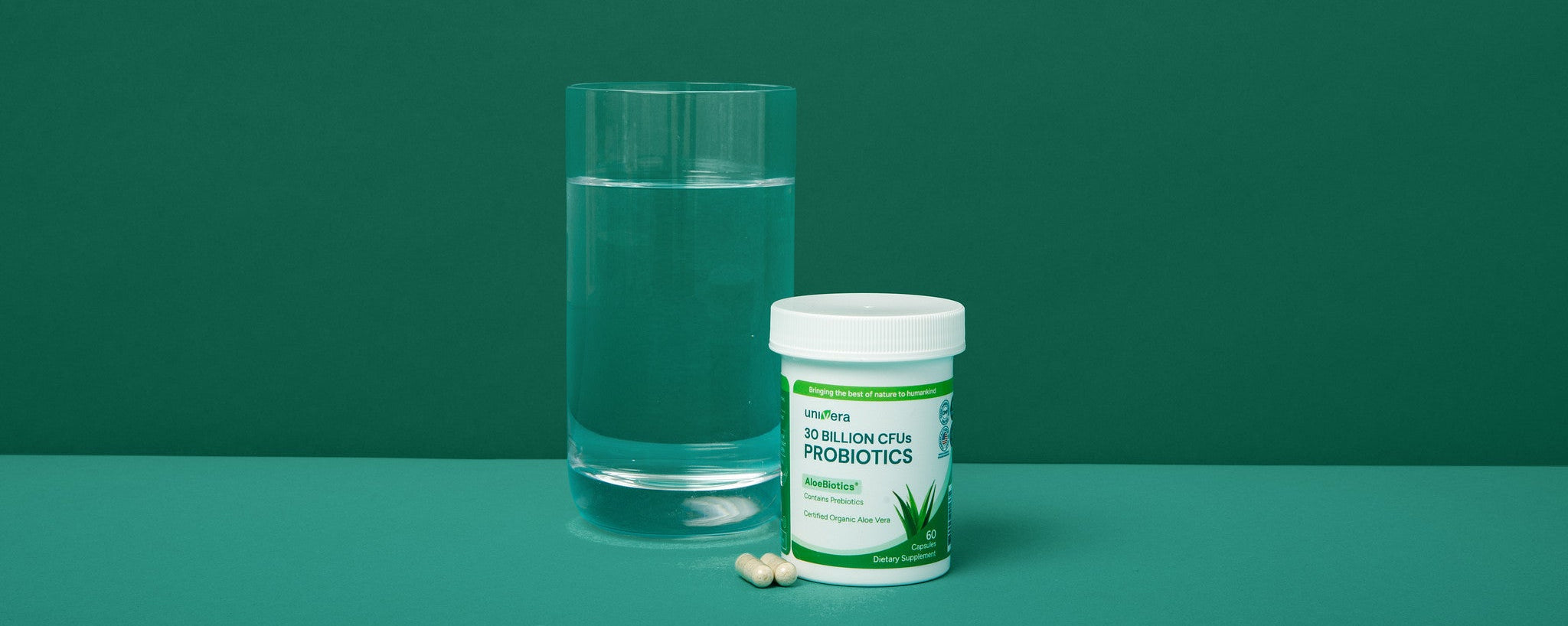 Probiotic supplement container with a glass of water on a green background