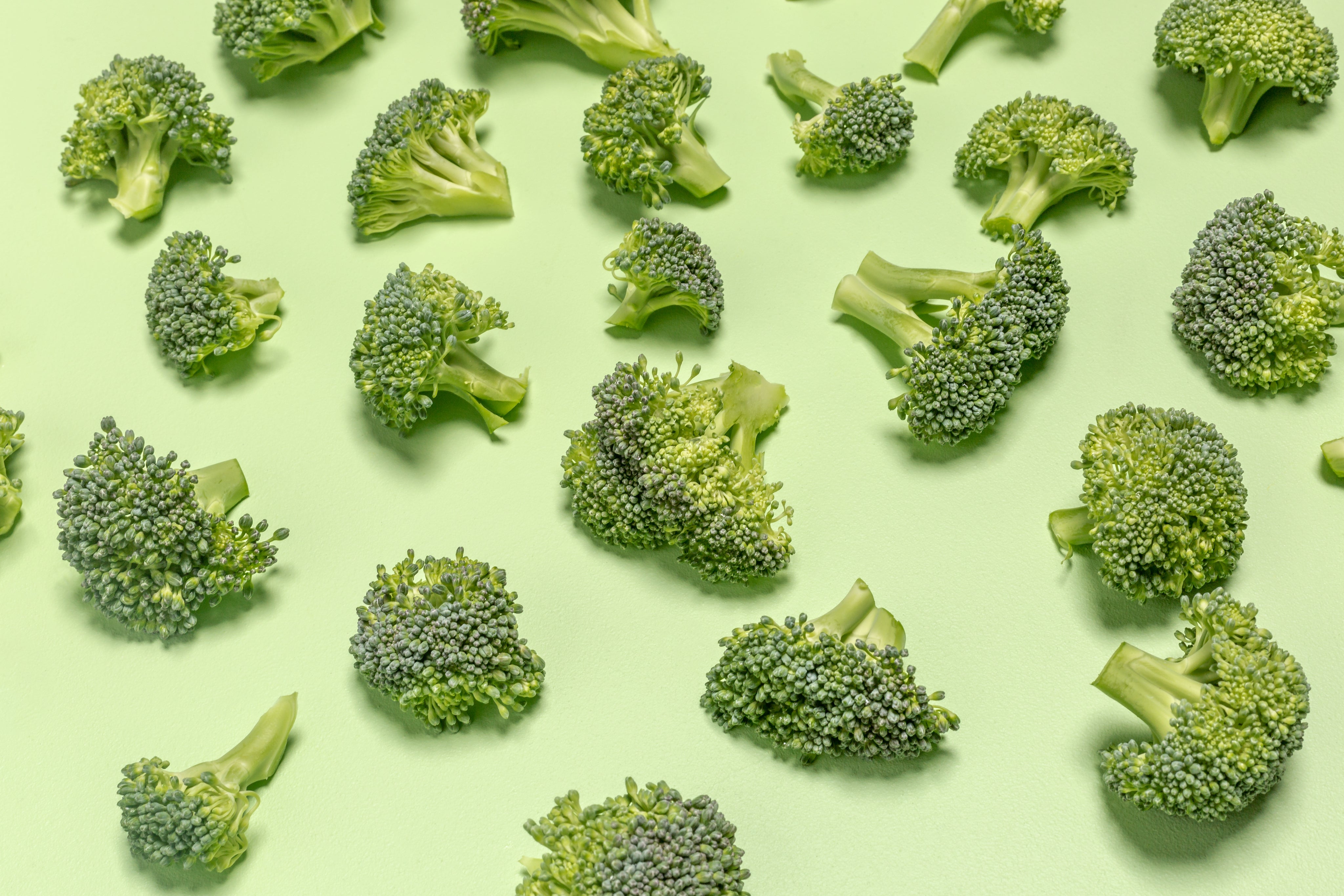 Fresh broccoli pieces arranged on a green surface, highlighting natural, healthy vegetables rich in nutrients